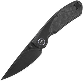 A folded knife with a black stonewash finish titanium handle and carbon fiber inlay, featuring a black blade with the Bestech Knives logo near the tip.