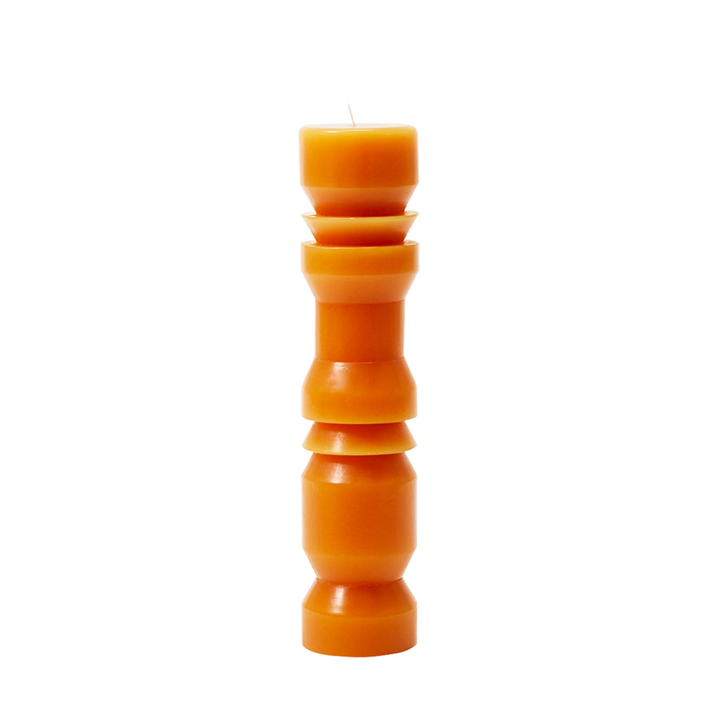 A large terracotta-colored pillar candle with a unique, tapered shape, designed by Grain for Areaware.