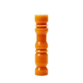 A large terracotta-colored pillar candle with a unique, tapered shape, designed by Grain for Areaware.