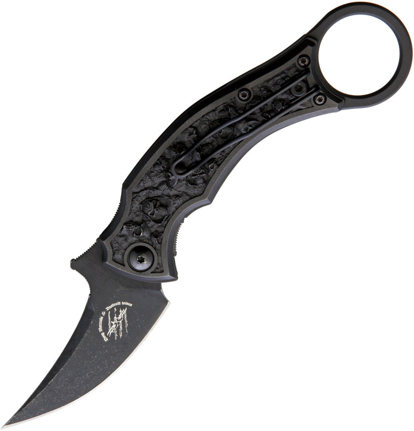 A folding knife with a black stonewash finish blade and a sculpted bronze handle with a finger ring and pocket clip. The knife is closed and displays the brand name 'Bastinelli Creations' on the blade.
