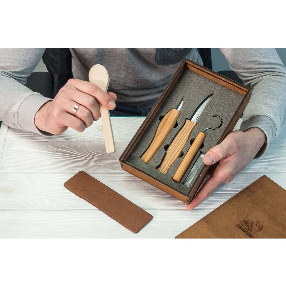A person is carving a spoon with a knife in a special gift-box that contains three knives and accessories for spoon carving. BeaverCraft | KIng of Knives e-store