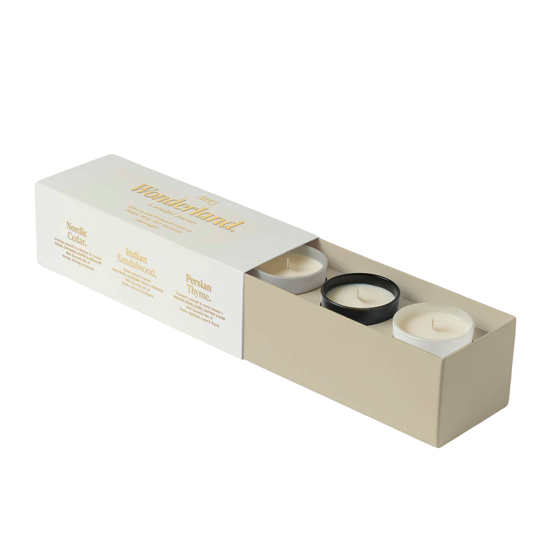 A set of three beeswax candles in matte colored ceramic pots, presented in a gold foiled gift box with the brand name 'Aery Living' on it.