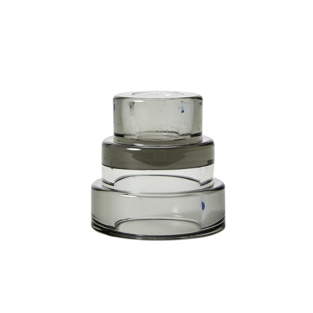 A grey, glass candle holder with a layered design resembling terraced hillsides.