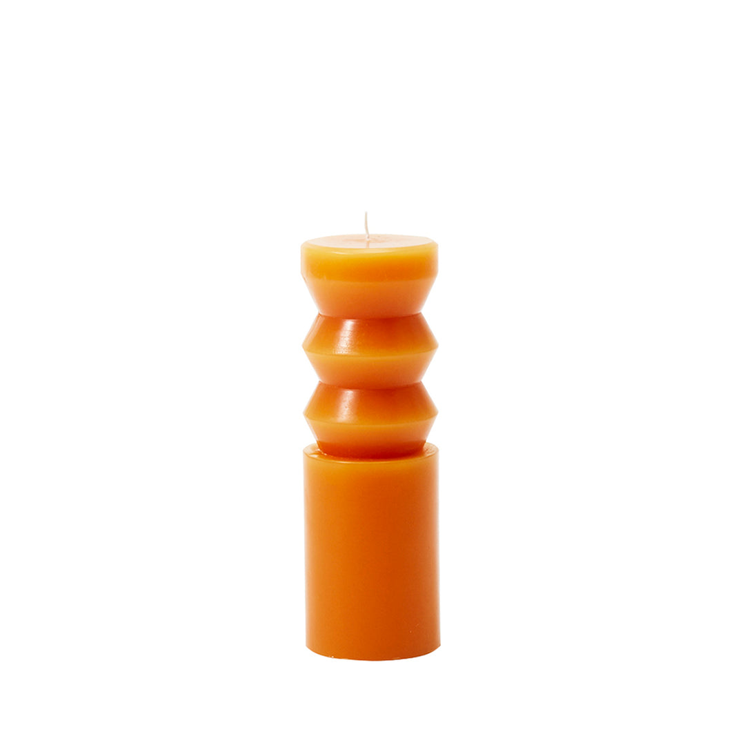 A medium-sized orange paraffin wax candle with a unique, sculpted design, resembling a totem, from the Areaware brand.