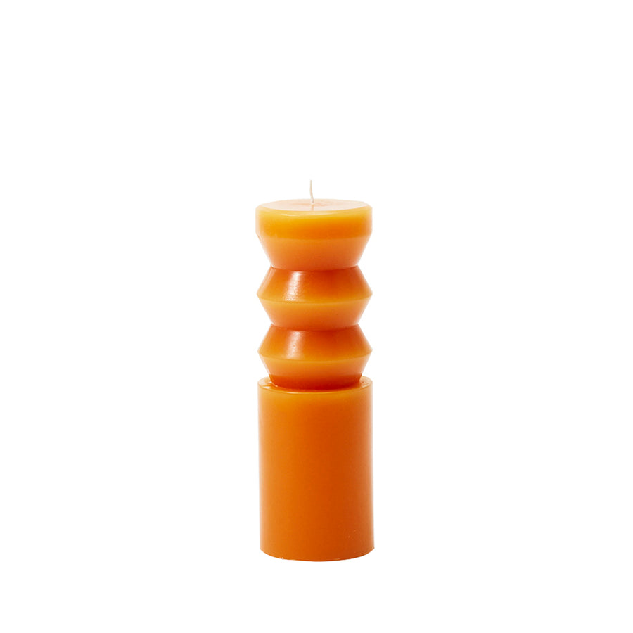 A medium-sized orange paraffin wax candle with a unique, sculpted design, resembling a totem, from the Areaware brand.