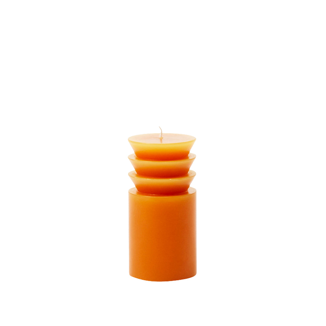 A small orange pillar candle with a unique, textured surface, designed by Grain for Areaware.